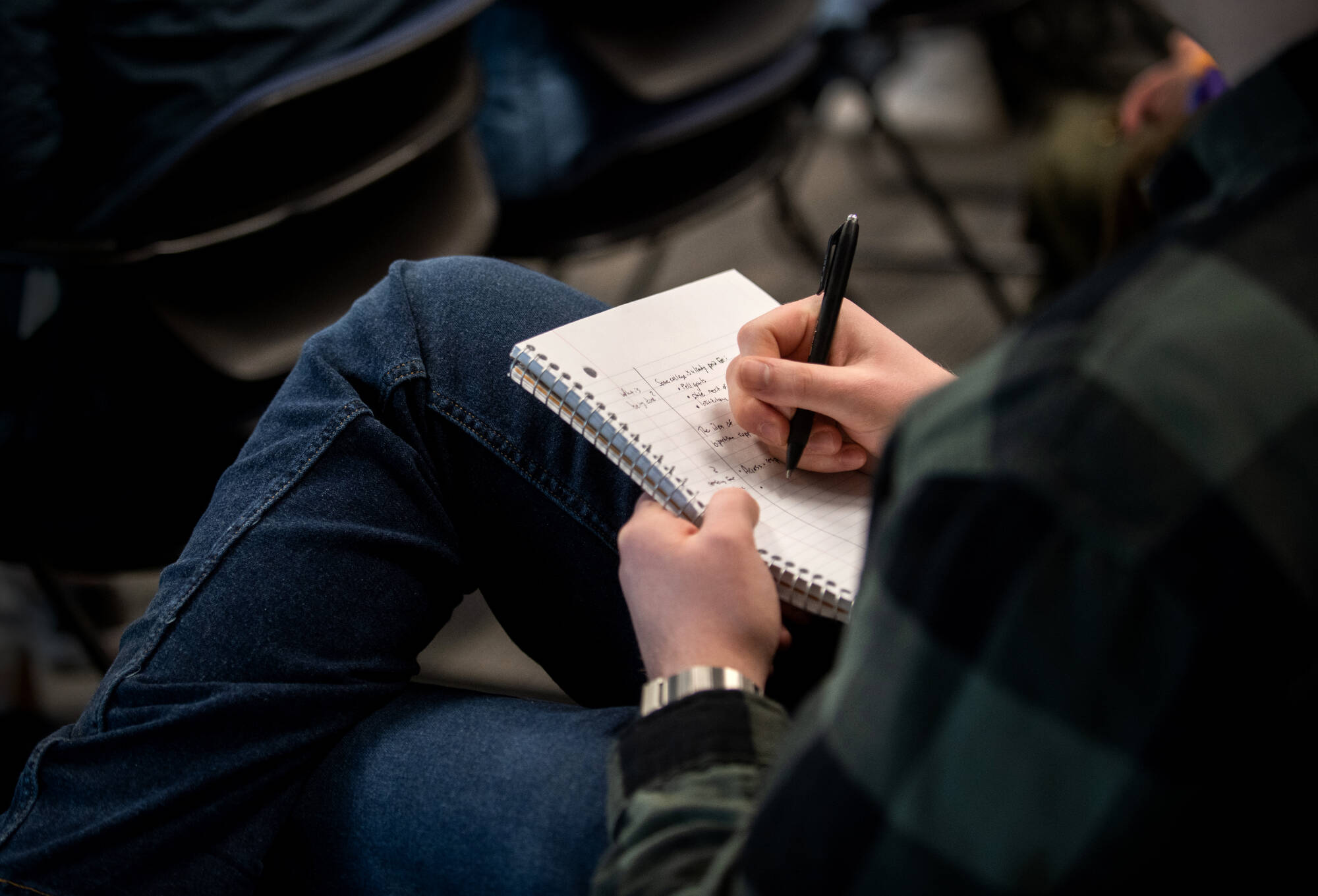 close up of student taking notes in a notebook on their lap
